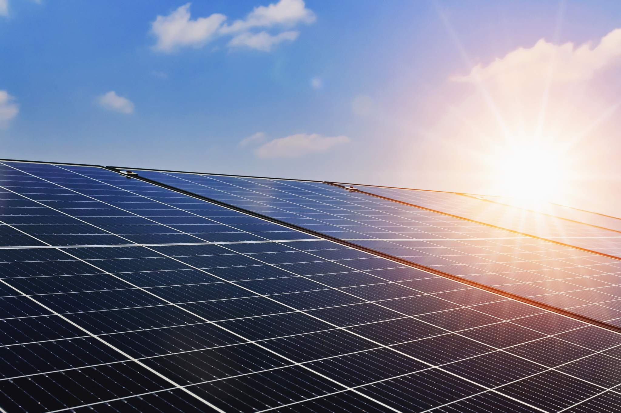 Solar panels against a blue sky with sun shining down