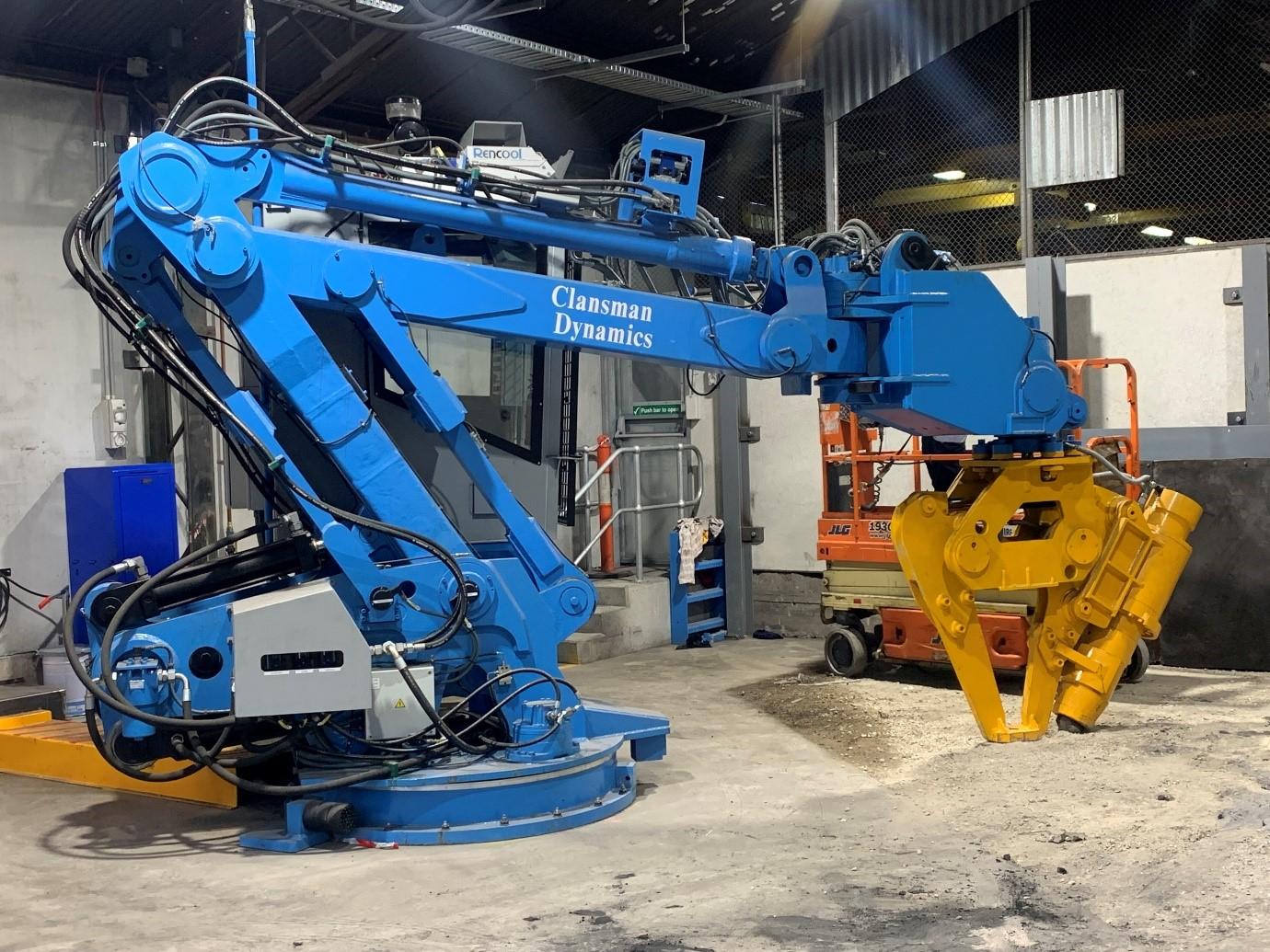 large blue and yellow mechanical arm on concrete factory floor